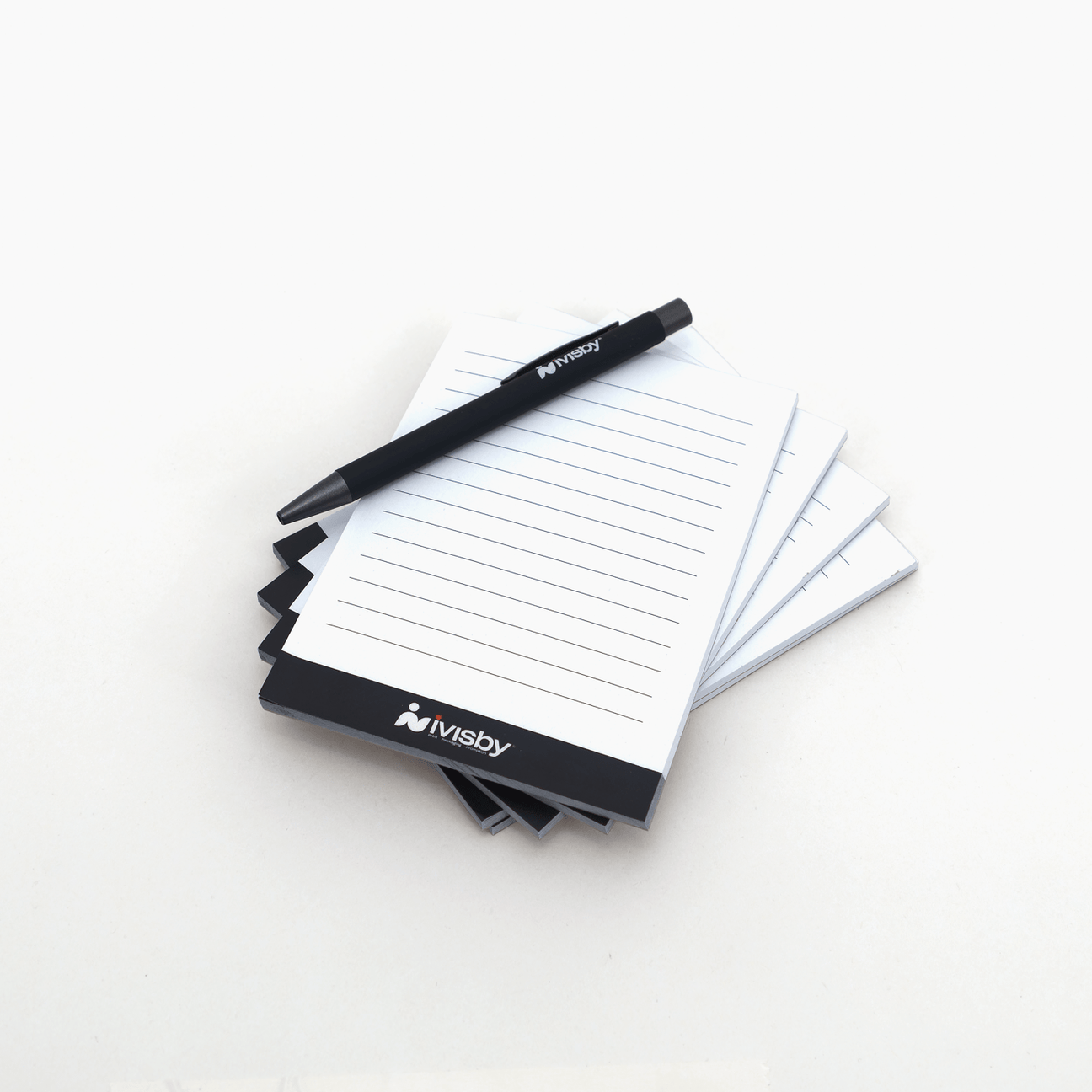 Anteckningsblock med iVisby-logotyp och linjerade sidor, tillsammans med en svart iVisby-penna.