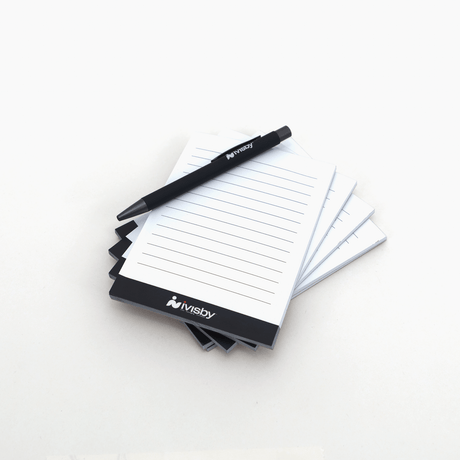 Anteckningsblock med iVisby-logotyp och linjerade sidor, tillsammans med en svart iVisby-penna.